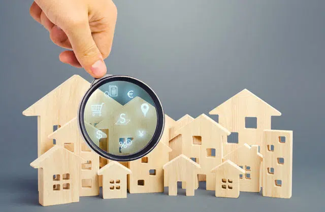 Realtor examines houses through a magnifying glass. Review of the real estate market, search for the best offers based on the criteria of price, location, area, infrastructure. Customer preferences. L'apporteur d'Immo
