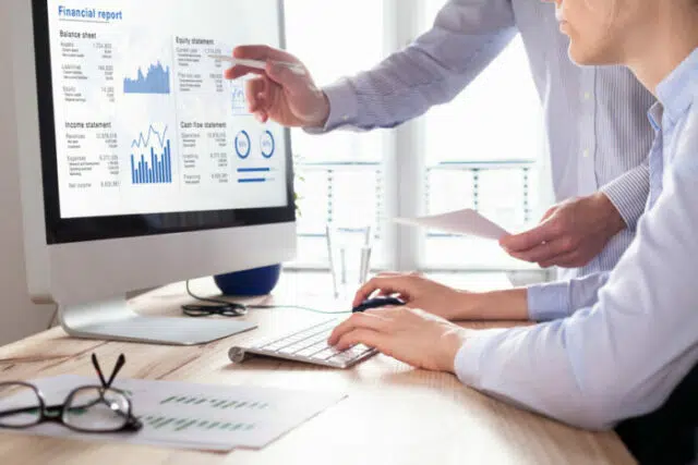 Consulting auditors auditing financial report on computer screen