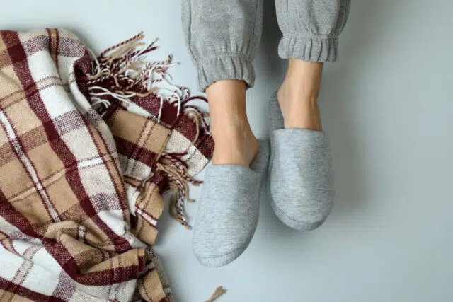 Female legs in gray slippers on gray background pantoufle