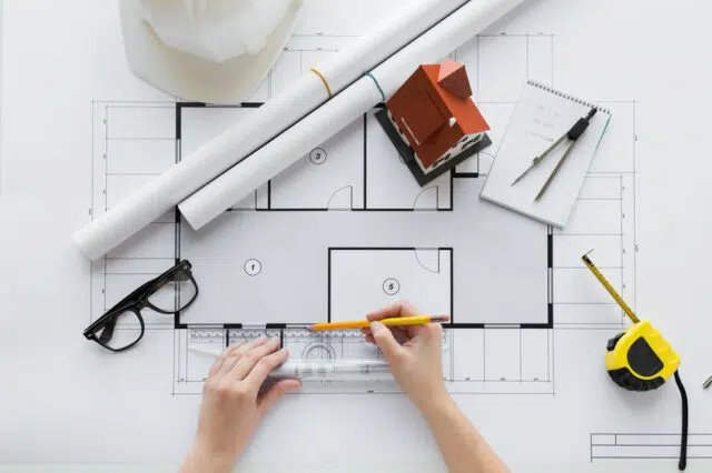 close up of hands with ruler measuring blueprint