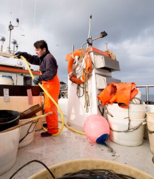 Fisherman hosing down fishing boat