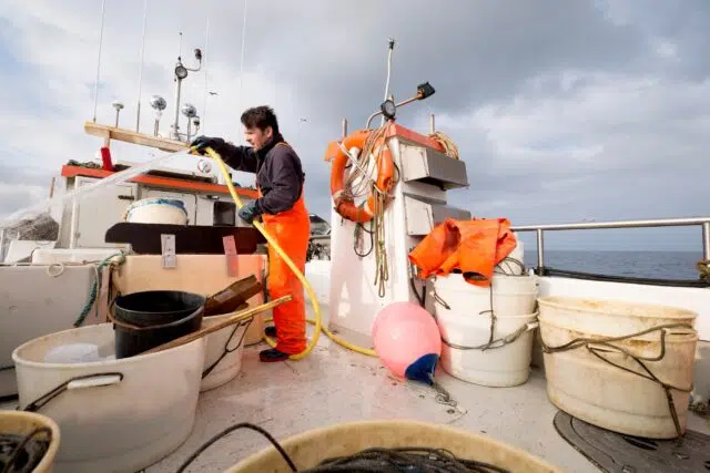 Fisherman hosing down fishing boat Fisherman hosing down fishing boat