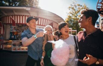 Group of friends eating candyfloss at fairground