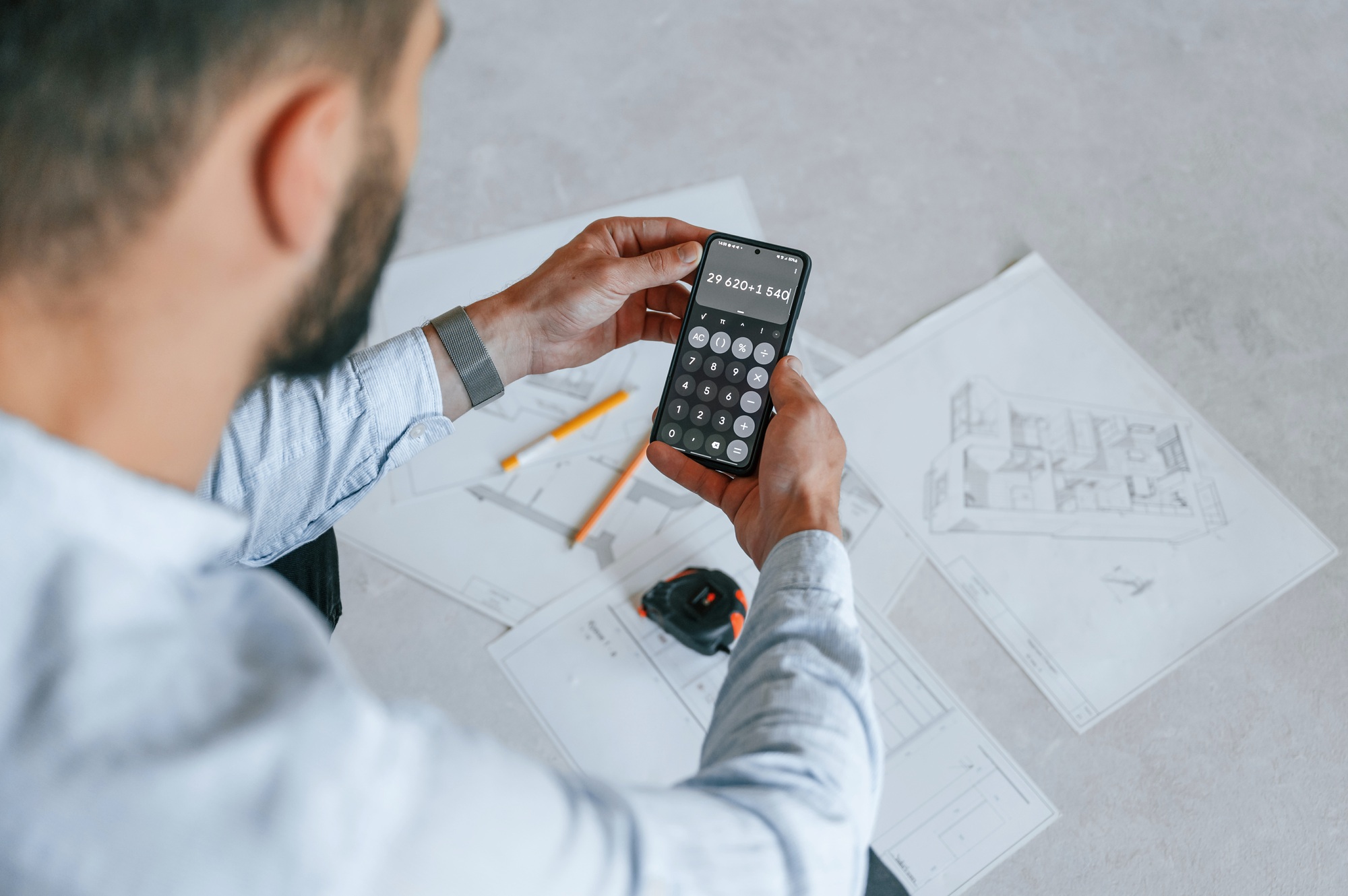 Calculating numbers by using smartphone. The man is making repairs in the apartment