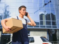 Deliveryman in uniform holds parcel and phone