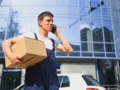 Deliveryman in uniform holds parcel and phone