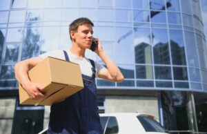 Deliveryman in uniform holds parcel and phone