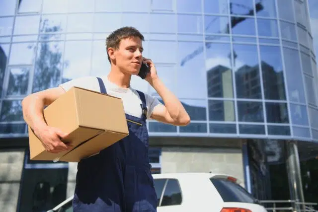 Deliveryman in uniform holds parcel and phone Deliveryman in uniform holds parcel and phone