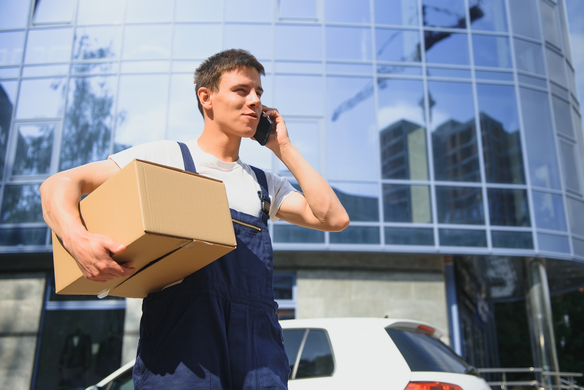 Deliveryman in uniform holds parcel and phone