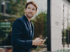 Pensive businessman holds cellular sends text messages dressed formally