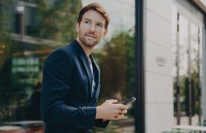 Pensive businessman holds cellular sends text messages dressed formally