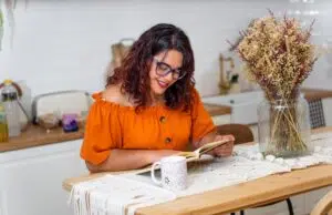 Young book-loving daughter reading in the kitchen.