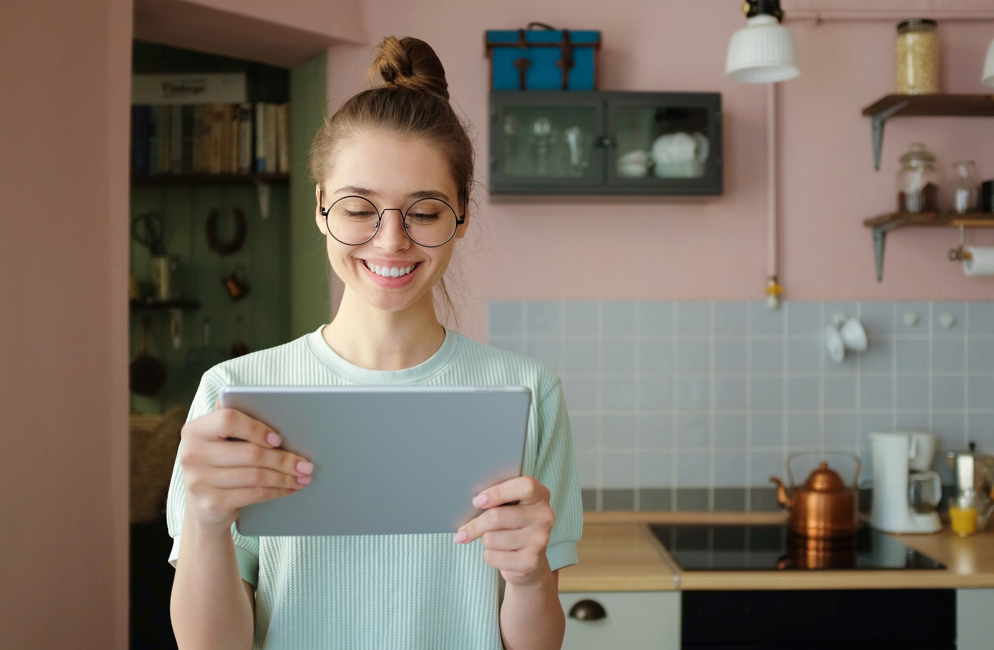 Young good-looking woman looks at tablet PC with smile, laughing while sending sms