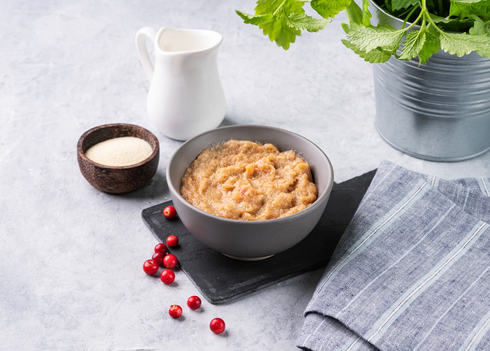 Semolina porridge with red berries in a bowl on a blue background with milk.