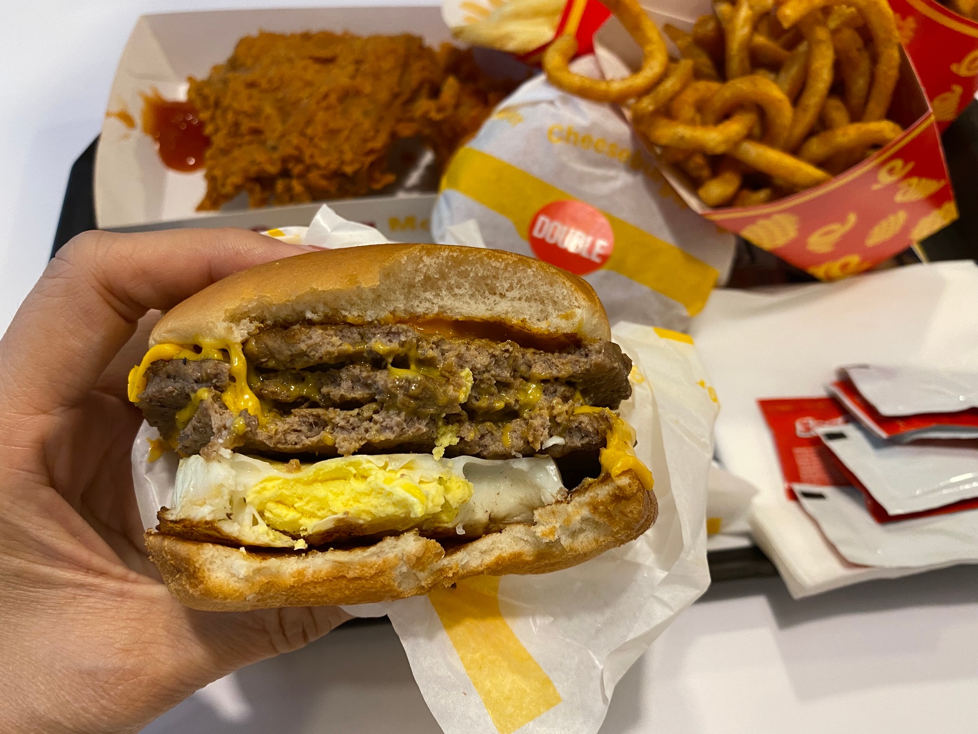 Half eaten spicy triple beef burger with cheese and egg