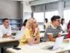 High school science class: A boy and girl using a laptop computer while attending to the teacher