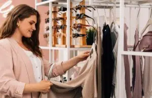 Side view of a smiling plus size woman shopping in a small clothing store