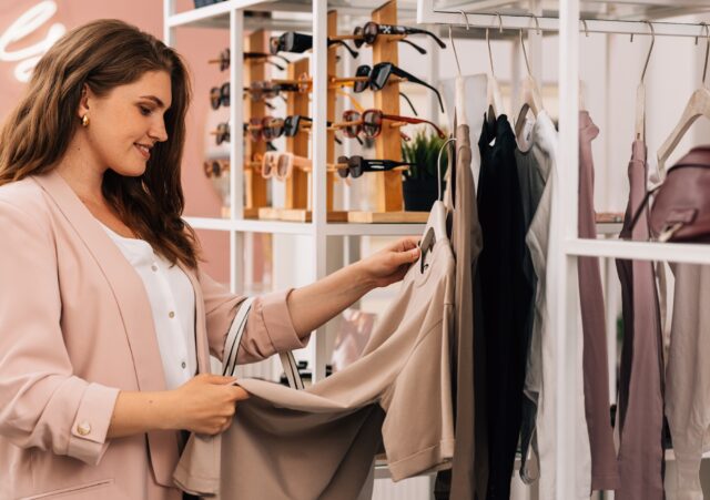 Side view of a smiling plus size woman shopping in a small clothing store