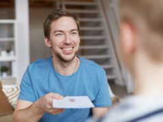 Smiling father giving birthday card to son