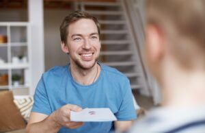 Smiling father giving birthday card to son