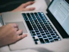 Using laptop MacBook working typing social media at home mobile technology digital work keyboard