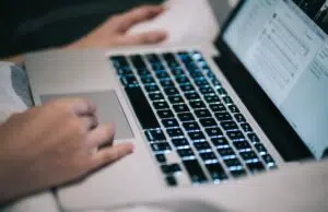 Using laptop MacBook working typing social media at home mobile technology digital work keyboard