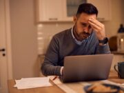 Worried businessman reading problematic e-mail on laptop at home.